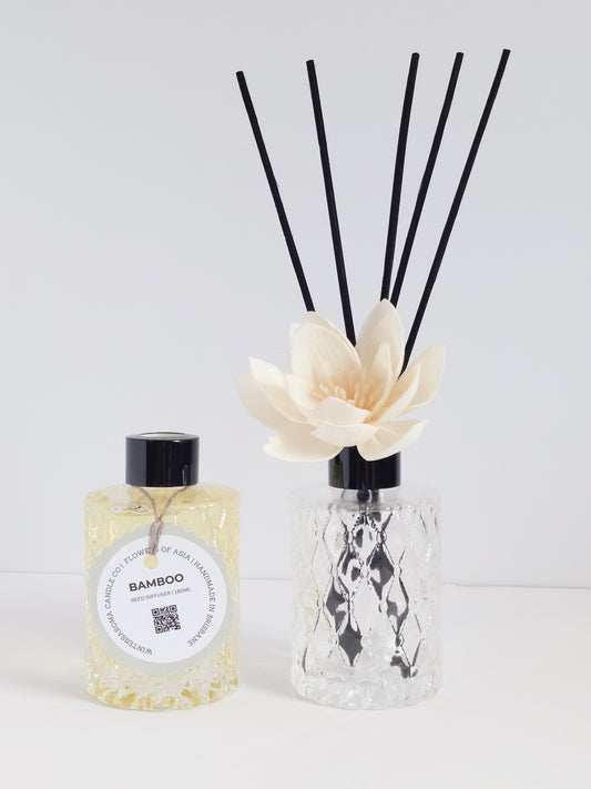 Two clear reed diffusers with bamboo-scented oil and several bamboo reeds, alongside a smaller bottle of the same scent.