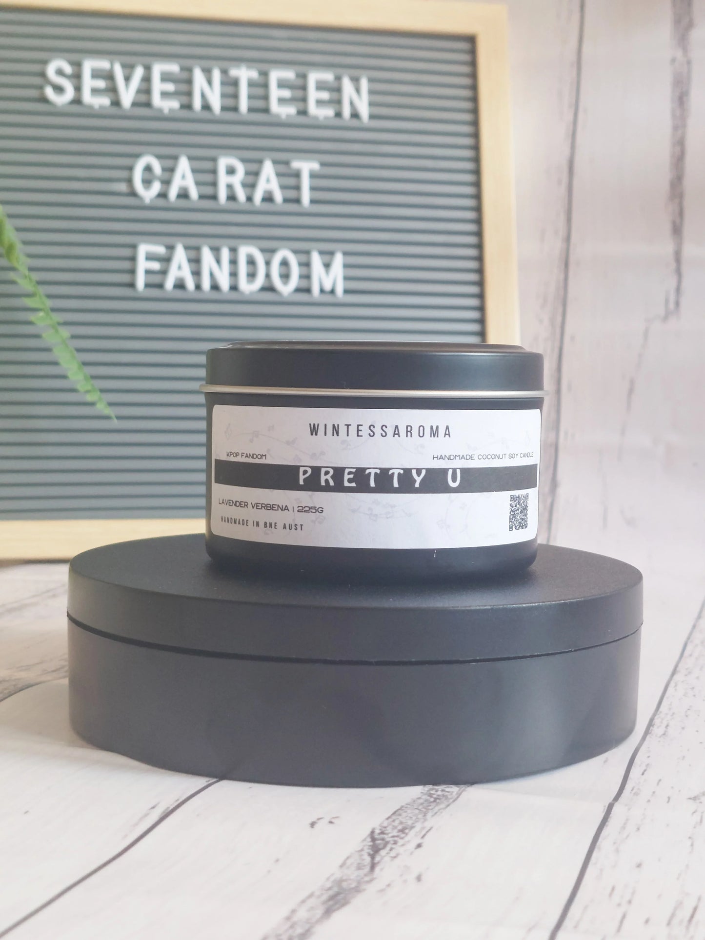 Candle labeled 'Pretty U' by Wintessaroma on a wooden surface with a letterboard in the background. Front View