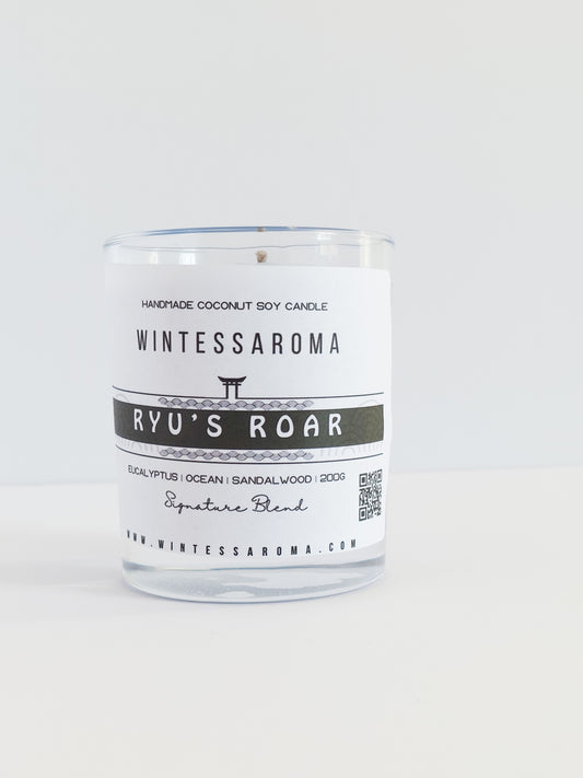 A clear glass candle with a white label that reads 'Wintessaroma' and 'Ryu's Roar'. The label includes the scent notes of citrus and eucalyptus.