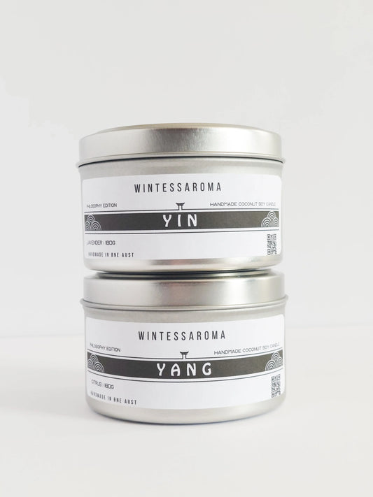 A set of two candles with labels indicating 'WINTESSAROMA' and different scents, placed on a white background.